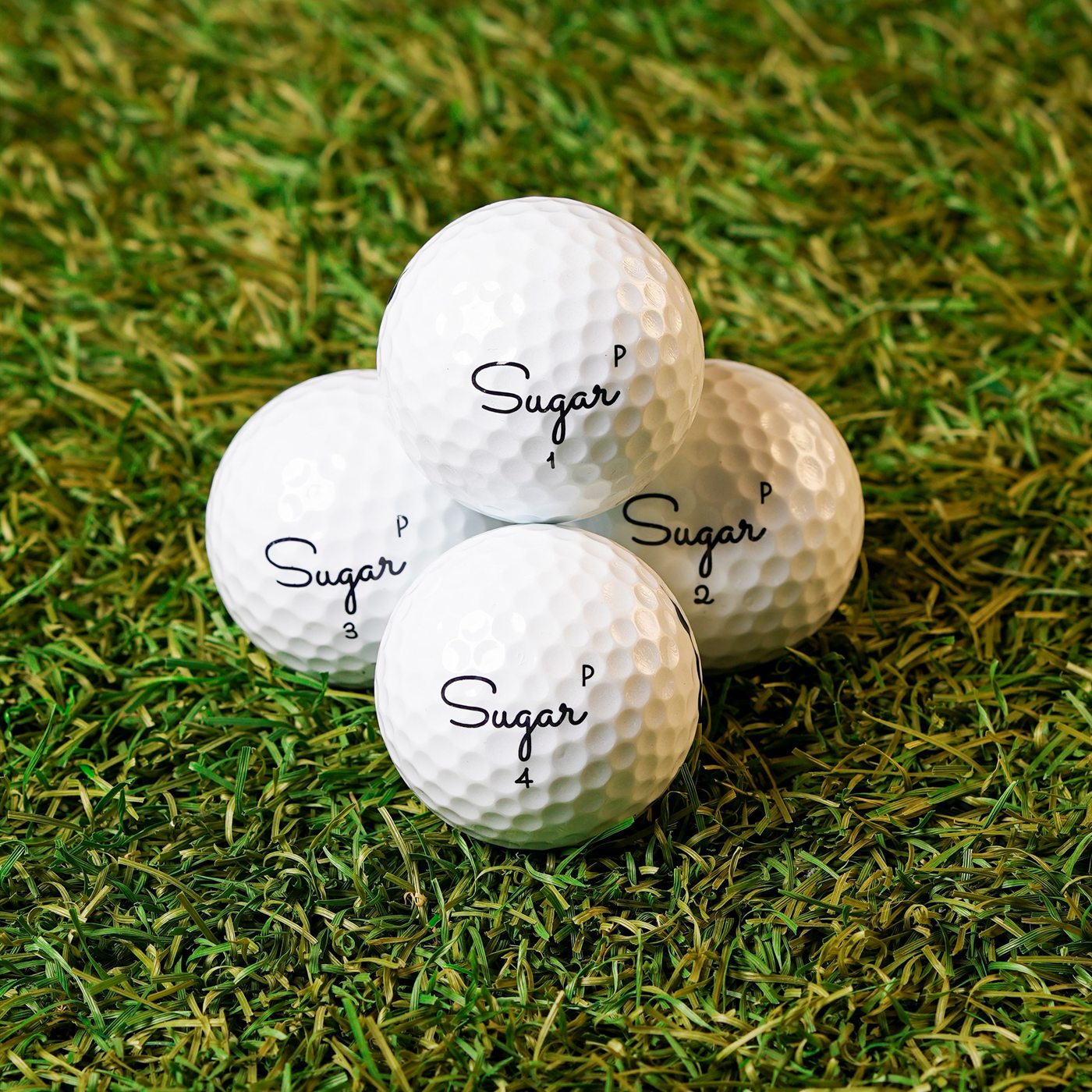 A stack of Sugar Pure golf balls on the turf, P stamps showing