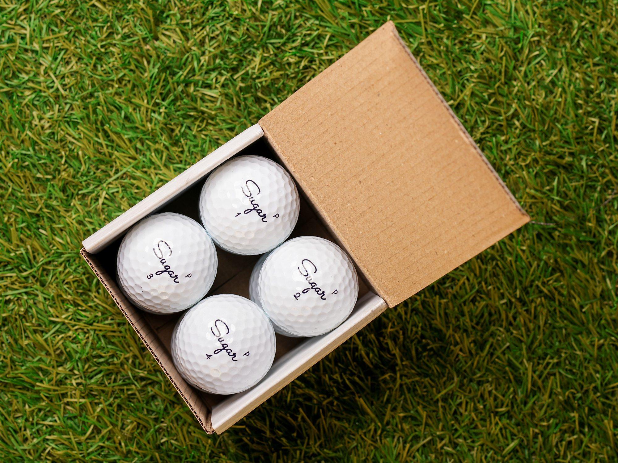 An open Sugar Golf cube on the grass with the balls inside