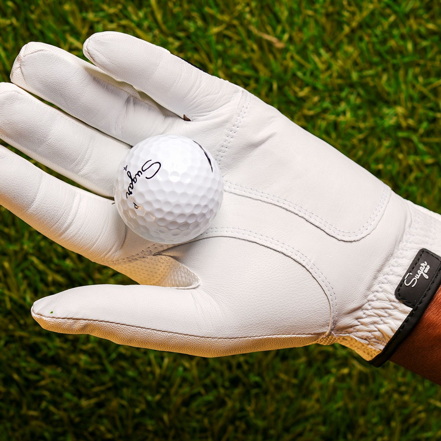A Sugar Golf glove holding a Sugar ball in the palm